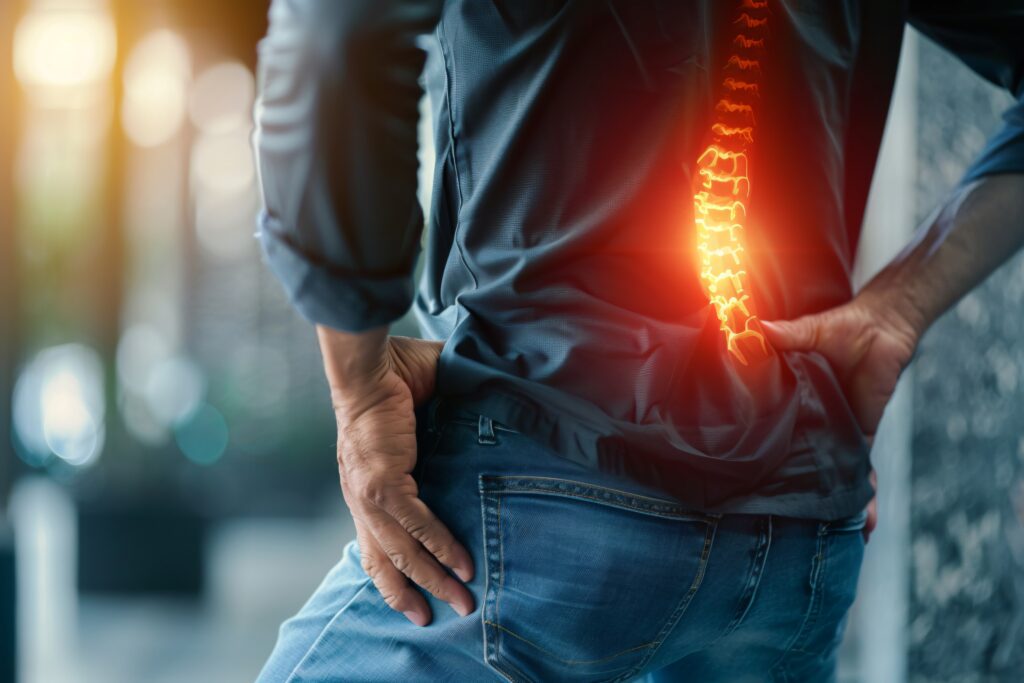 man is grabbing his lower back pain with visible spine highlighted