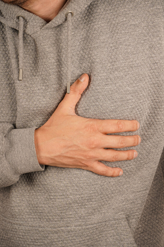 person clasps their stomach with hand symbolizing pain illness clean background focuses gesture clear representation discomfort unease